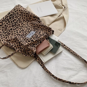 Flat lay of a leopard print canvas tote bag with a notebook and autumn accessories