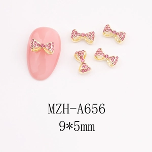 Macro shot of 9x5mm pink rhinestone bow nail art charm with gold alloy base and pink gem