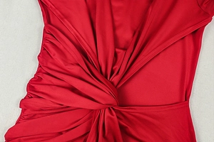Detailed macro view of the ruched waist knot and silky red fabric on this bodycon dress
