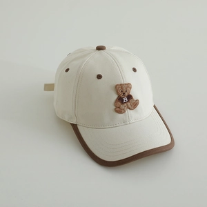 Détail de la casquette beige en coton avec broderie ours et bordure contrastée sur la visière