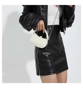 Detail of off-white canvas crossbody bag with metal chain strap and top handle