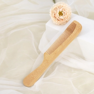 Eco-friendly bamboo hair comb displayed on a white minimalist pedestal with floral accents