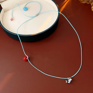 Detail of dachshund puppy pendant on a blue adjustable cord necklace with colorful beads