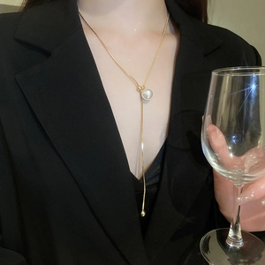 Close-up of golden pearl snake chain necklace worn with a elegant black blazer