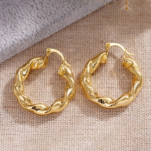 Makroaufnahme goldener gedrehter Creolen mit strukturierter Spiralform und Metallglanz