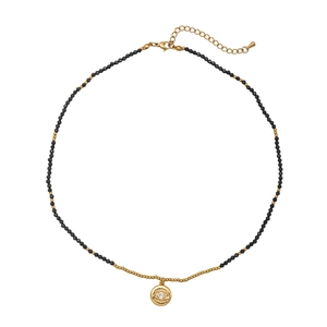 Beaded necklace with black spinel stones and golden evil eye charm on white background