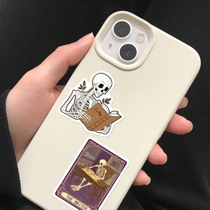 Gothic skull stickers on cream iPhone case showing skeleton reading life book and the writer
