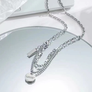 Macro view of layered steel necklace with engraved inspirational round pendant