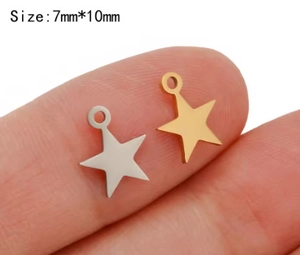 Macro shot showing gold and silver star pendants on a finger to demonstrate the 7x10mm size