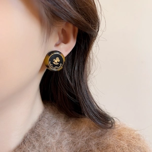 Détail d'une boucle d'oreille vintage ronde avec motif cheval doré sur le mannequin