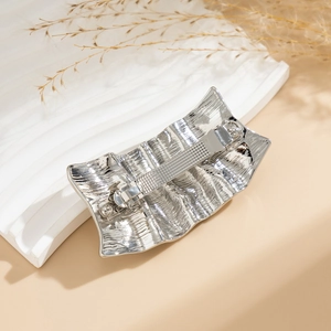 Detail of silver liquid metal hair clip showing irregular wave texture and spring buckle