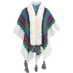Close-up of white knitted poncho with colorful geometric patterns and plush faux fur collar