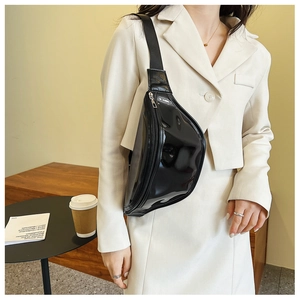 Detailed shot of a stylish black glossy chest bag worn by a model in a smart casual outfit.