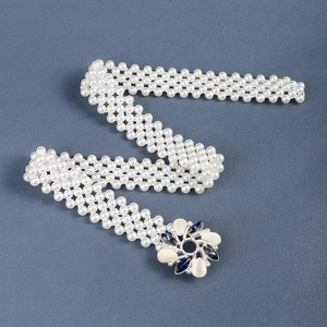 Detailed view of pearl belt with floral metal buckle featuring blue rhinestones and enamel