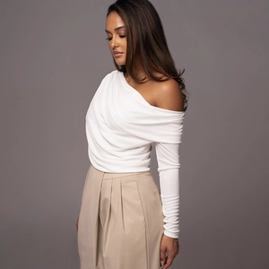 Detailed view of white off-shoulder long sleeve bodysuit with elegant pleated design texture