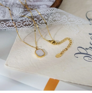 Detail of 18K gold titanium steel necklace with white shell pendant and lobster clasp