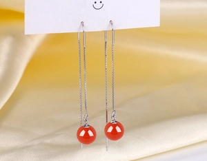 Detail of long silver tassel earrings with round red agate beads on white display card