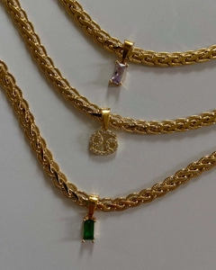 Close-up of gold braided necklaces with purple, emerald gemstones and zodiac charms