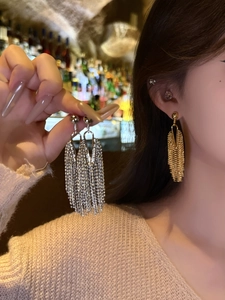 Close-up of gold and silver long chain tassel earrings showing metallic texture