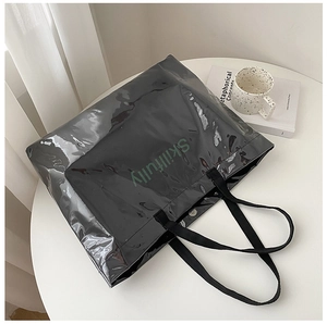 Detail of black glossy tote bag featuring green skillfully text and metal magnetic closure