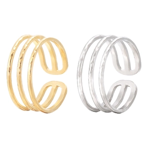 Detail of layered wavy open rings in gold and silver finish with hammered metal texture