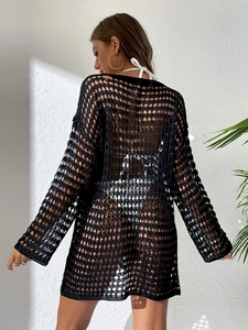 Détail de la texture en maille crochetée noire d'une robe de plage à manches longues évidée
