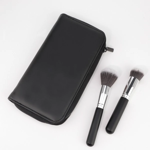 Détail de la pochette zippée en cuir PU noir avec pinceaux de maquillage