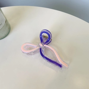 Elegant large bow hair claw clip with purple and pink ribbon design on white desk