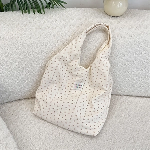 Detail of corduroy tote bag with floral print and white fabric label on soft texture