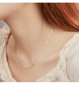Close-up of minimalist 925 sterling silver ball chain necklace worn on model neck