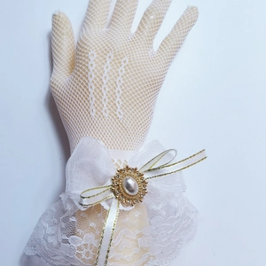 Macro shot of white lace bridal wrist cuff with golden bow and pearl center detail