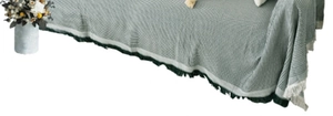 Detailed view of gray-green waffle texture sofa blanket with decorative fringe tassels