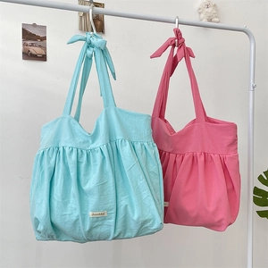 Detail of pleated canvas tote bags in blue and pink with decorative shoulder knots