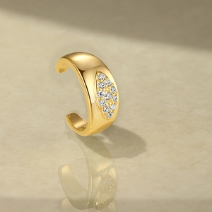 Detailed view of a gold marquise-cut ear cuff with sparkling zircon on marble surface