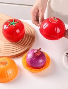 Detail showing hand opening a tomato shaped plastic food storage box for fresh produce