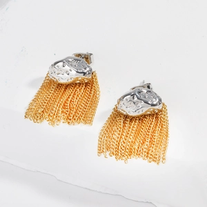 Vue détaillée de clous argentés martelés avec chaînes à pompons dorées sur fond blanc
