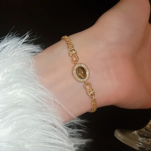 Détail d'un bracelet en chaîne gourmette dorée avec pierre brune ovale et halo de diamants