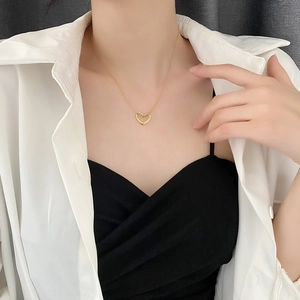 Elegant gold hollow heart pendant necklace worn by a model in a minimalist style
