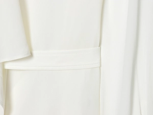 Detail shot of white asymmetric shirt showing chiffon texture and waist stitching