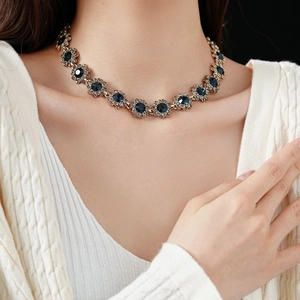 Vue détaillée d'un collier doré orné de gemmes bleues porté par un mannequin