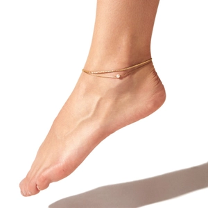 Double-layered gold chain anklet featuring a small pearl charm on a female ankle