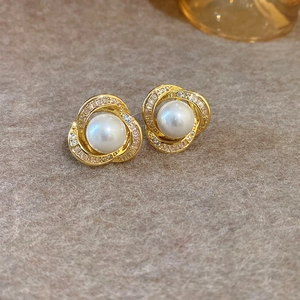 Gros plan de boucles d'oreilles dorées avec perles blanches et zircones cubiques sertis