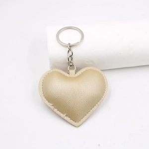 Detail shot of a golden heart-shaped leather keychain with fine stitching and metal ring