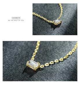 Close-up of rectangular zircon pendant on a gold cross chain necklace with 4-prong setting