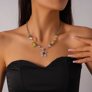 Détail d'un collier en perles de verre avec pendentif fleur argentée et breloque note de musique