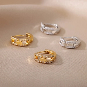 Macro detail of geometric C-shaped earrings with gold and silver finishes and micro-pavé zircons