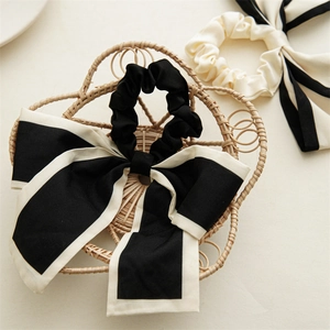 Detail of a black and white striped bow scrunchie with long ribbons on a woven tray