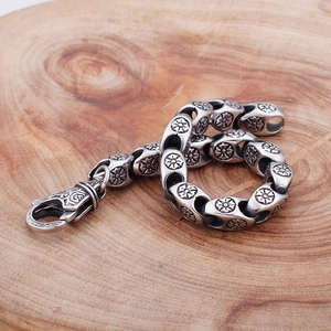 Detail of vintage punk stainless steel bracelet with floral carvings on wooden background