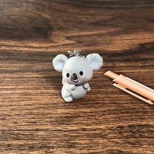 Close-up of cute grey resin koala keychain charm on a dark wood background