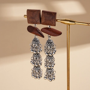 Close-up of Bohemian tiered Jhumka earrings with dark wood square studs and silver tassels
